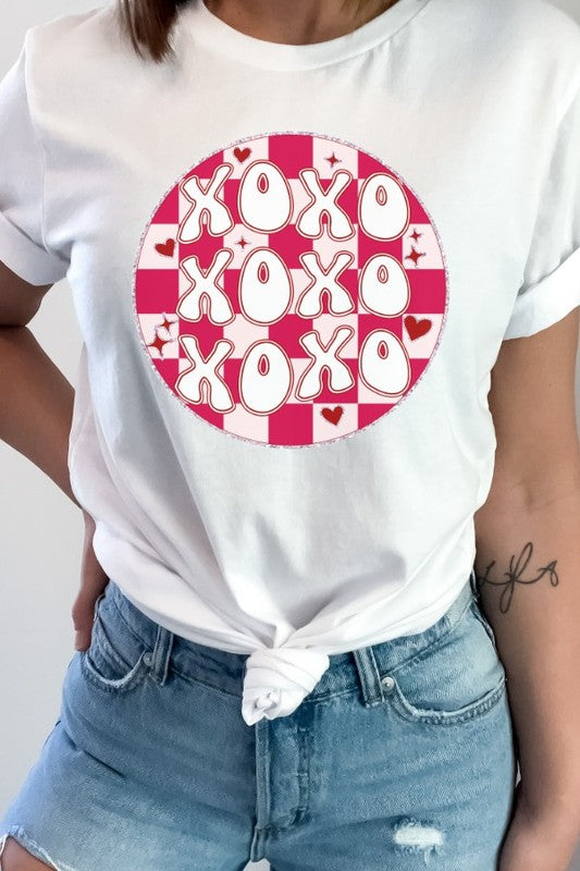 A person wearing a white t-shirt with a red and pink checkered pattern on it, and the text 'XOXO' in the center.