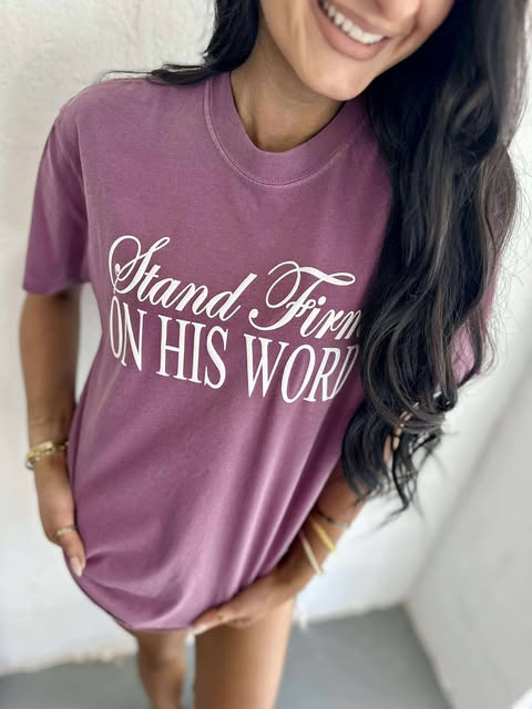 A person wearing a purple t-shirt with the text 'Stand Firm ON HIS WORD' printed in white.