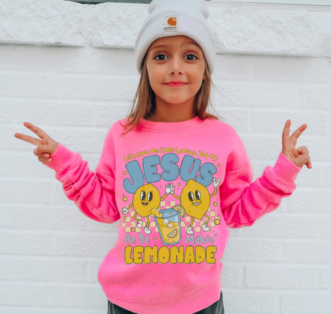 Child wearing a pink sweatshirt with colorful graphics and text, standing against a white background.