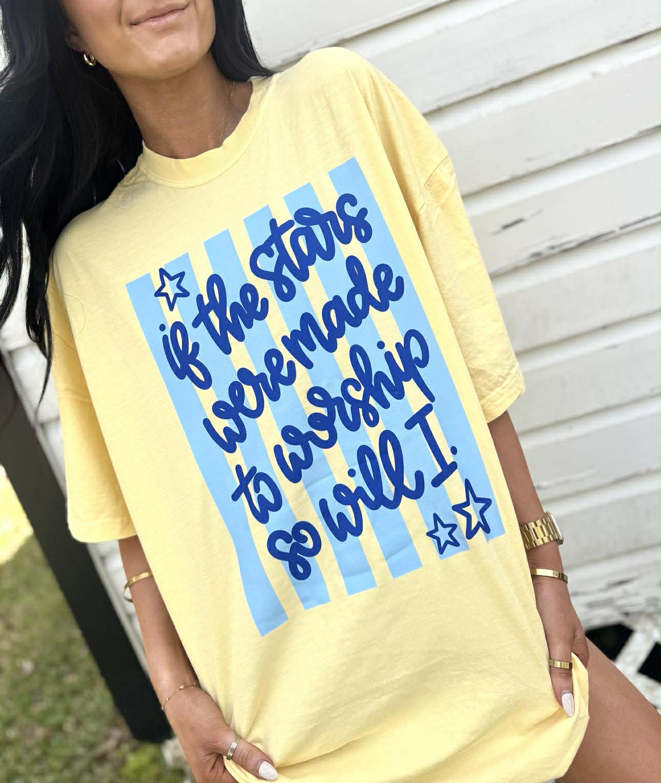 Person wearing a yellow t-shirt with blue text design "If the stars were made to worship so will I"