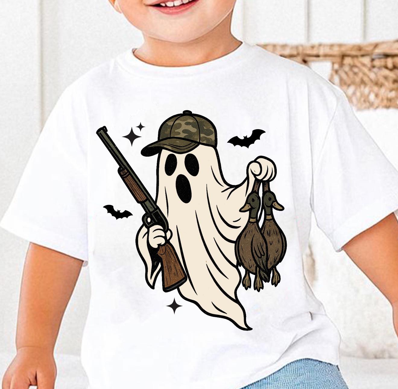 Child wearing a white t-shirt with a camo ghost holding a gun and two ducks design.